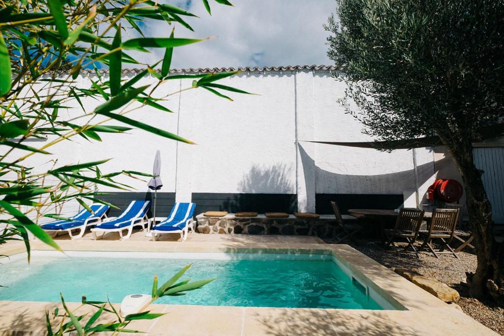 une piscine avec des chaises bleues et une clôture dans l'établissement Bergerie saint-claude, à Bessan