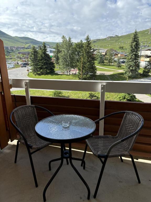 une table et deux chaises sur un balcon avec vue dans l'établissement logement chaleureux 1 chamb pied des pistes, à Huez
