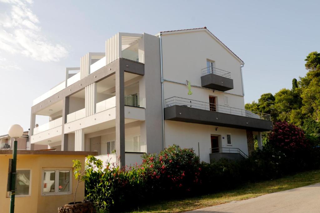 Biały budynek z balkonami na boku w obiekcie Apartmani Mary 2 plus 1 w mieście Kukljica