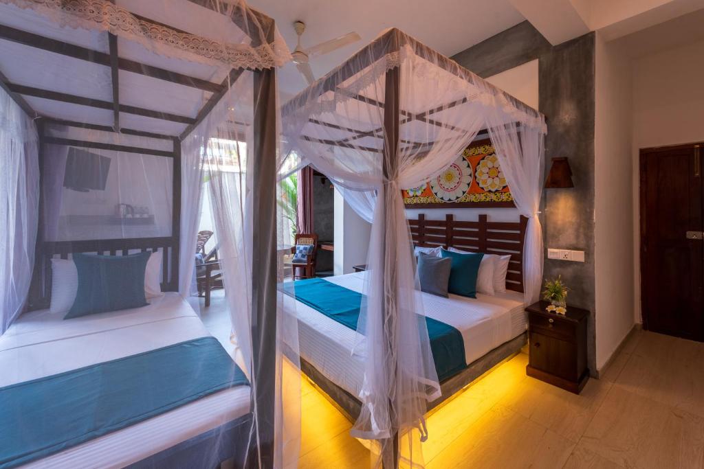 a bedroom with two beds and a canopy bed at Anama by Queens Mount in Tangalle