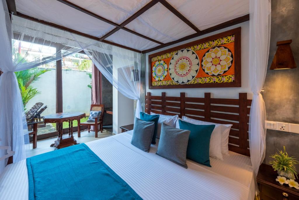 a bedroom with a large bed with blue pillows at Anama by Queens Mount in Tangalle