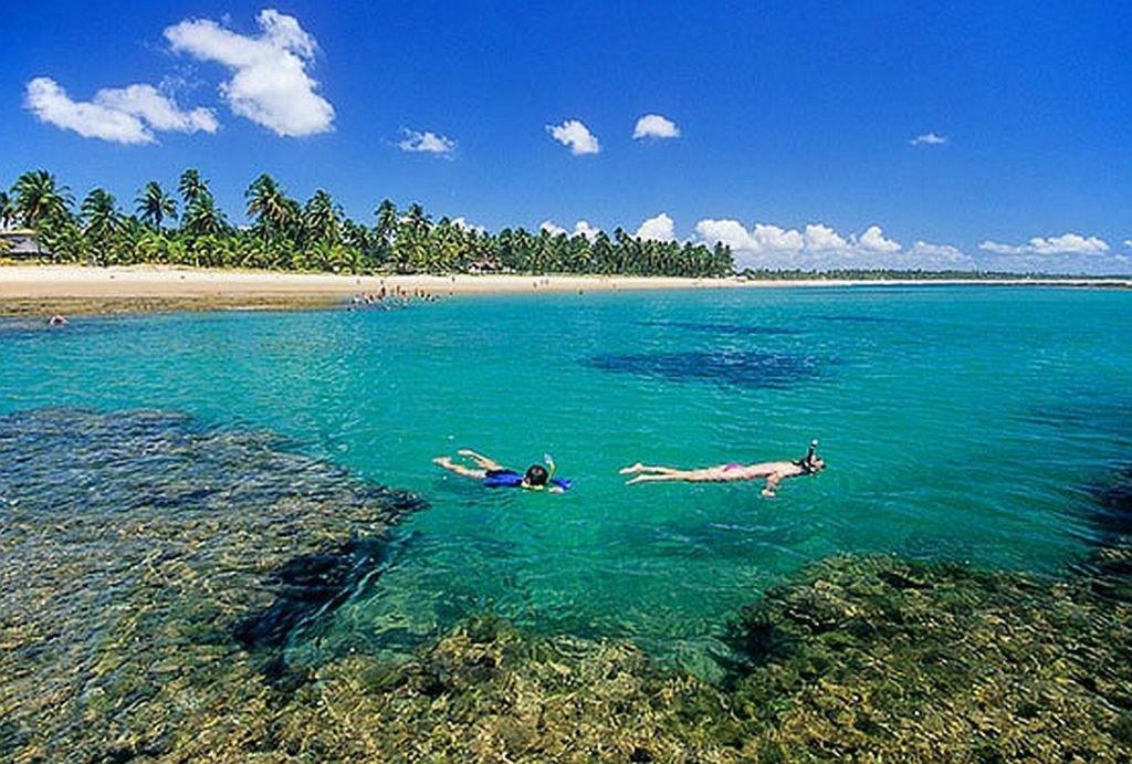 two people swimming in the water near a beach at Taipu - BEM PERTO das Piscinas Naturais in Marau