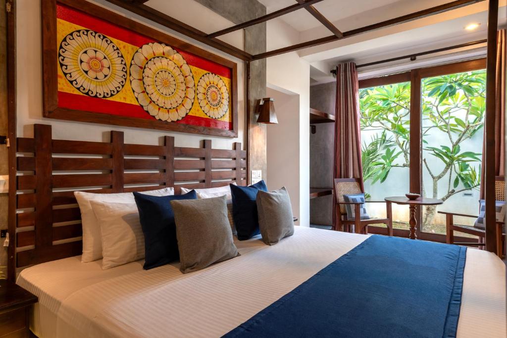 a bedroom with a large bed with blue and white pillows at Anama by Queens Mount in Tangalle