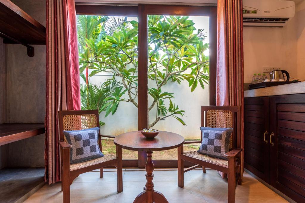 a room with a table and two chairs and a plant at Anama by Queens Mount in Tangalle