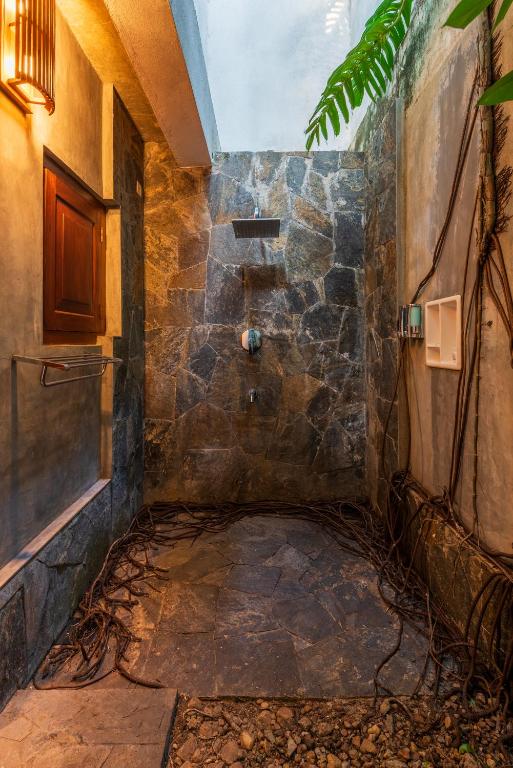 a walk in shower in a room with a stone wall at Anama by Queens Mount in Tangalle
