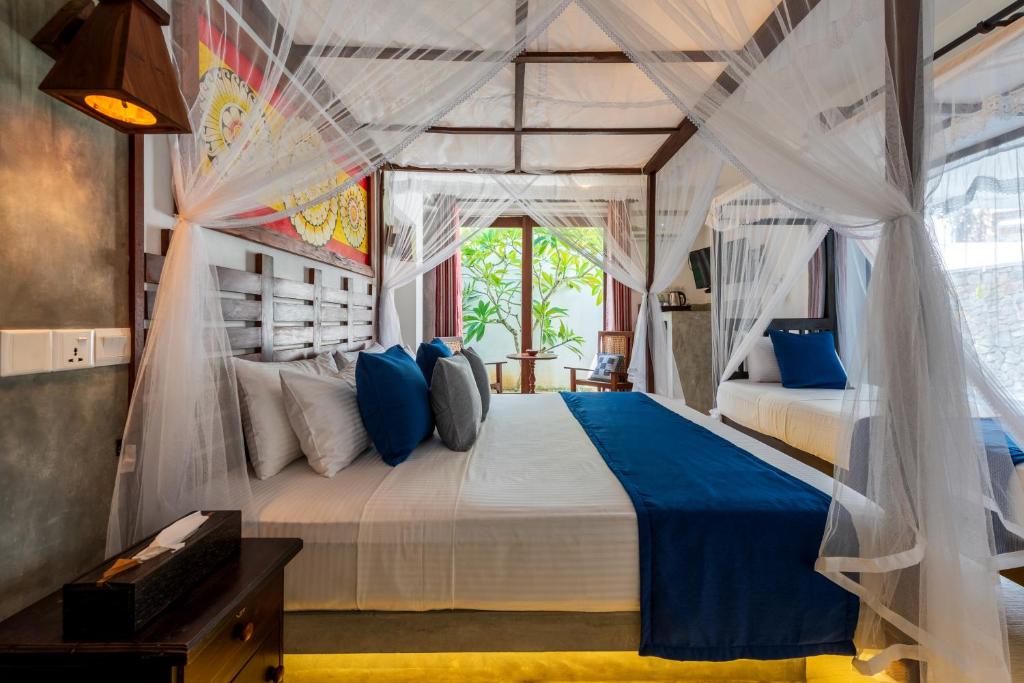 a bedroom with a large bed with blue pillows at Anama by Queens Mount in Tangalle