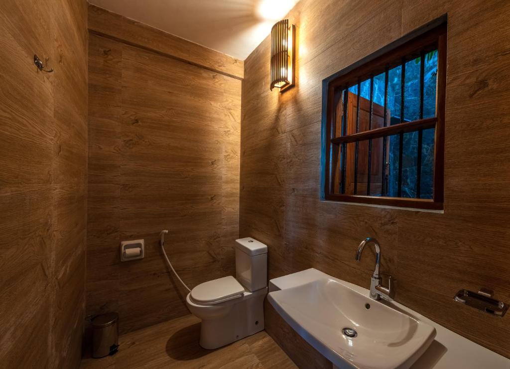 a bathroom with a toilet and a sink and a window at Anama by Queens Mount in Tangalle