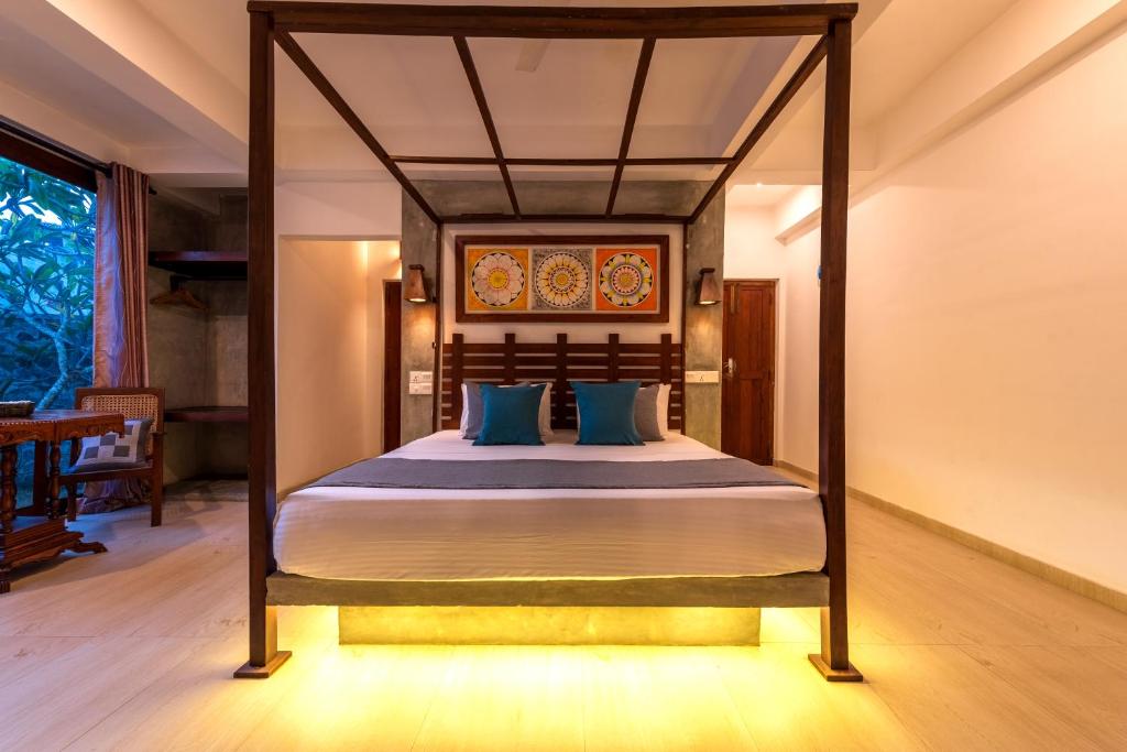 a bedroom with a canopy bed with blue pillows at Anama by Queens Mount in Tangalle