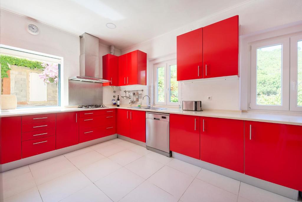 a red kitchen with white counters and red cabinets at Beach & Nature Villa with Amazing Pool by TimeCooler in Setúbal