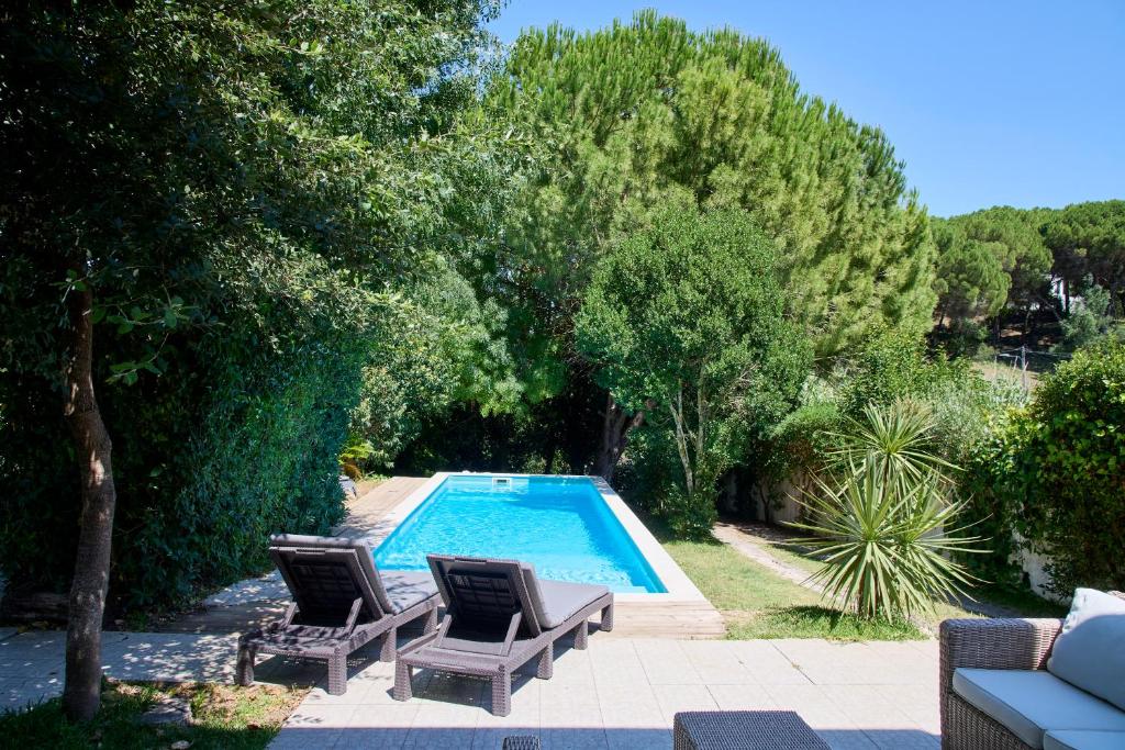 a swimming pool with two lounge chairs next to at Beach & Nature Villa with Amazing Pool by TimeCooler in Setúbal