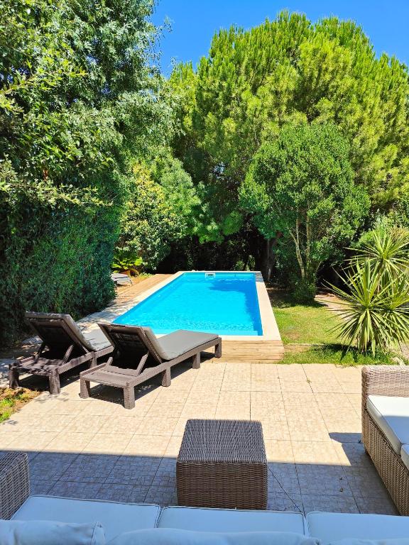 a swimming pool with two loungers and two chairs by it at Beach & Nature Villa with Amazing Pool by TimeCooler in Setúbal