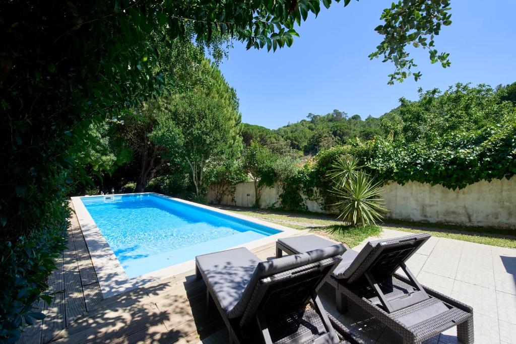 a swimming pool with two chairs and a table at Beach & Nature Villa with Amazing Pool by TimeCooler in Setúbal