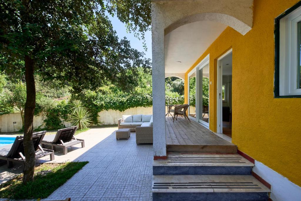 a patio with a couch and chairs on a house at Beach & Nature Villa with Amazing Pool by TimeCooler in Setúbal