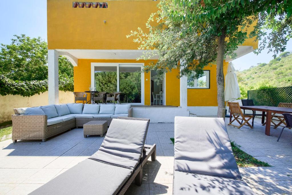 a patio with a couch and chairs in front of a building at Beach & Nature Villa with Amazing Pool by TimeCooler in Setúbal