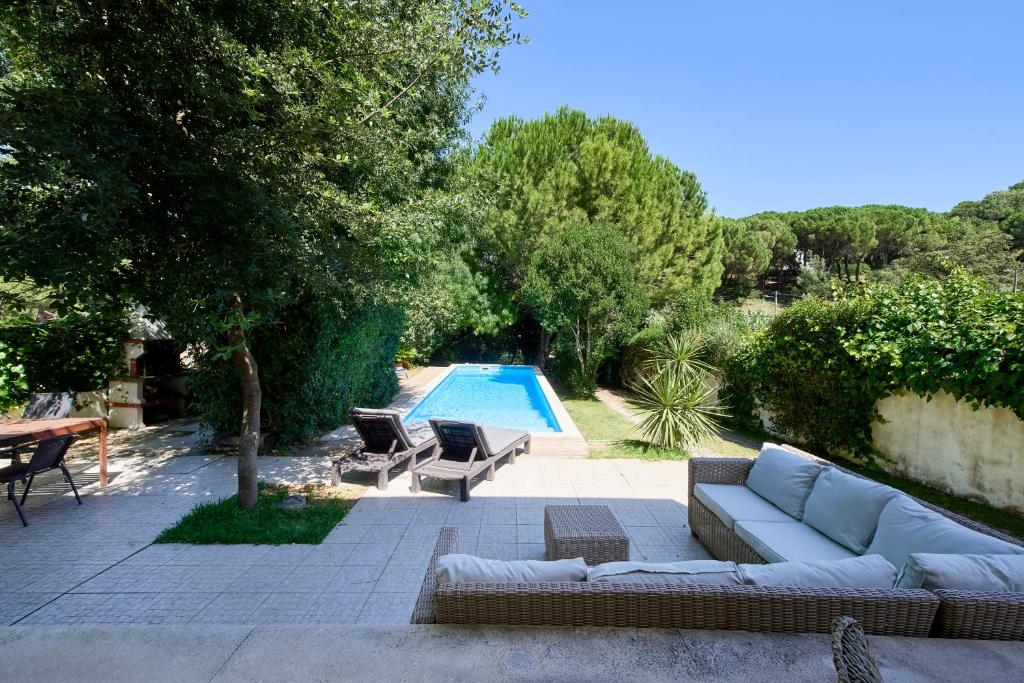 a patio with a couch and chairs next to a pool at Beach & Nature Villa with Amazing Pool by TimeCooler in Setúbal