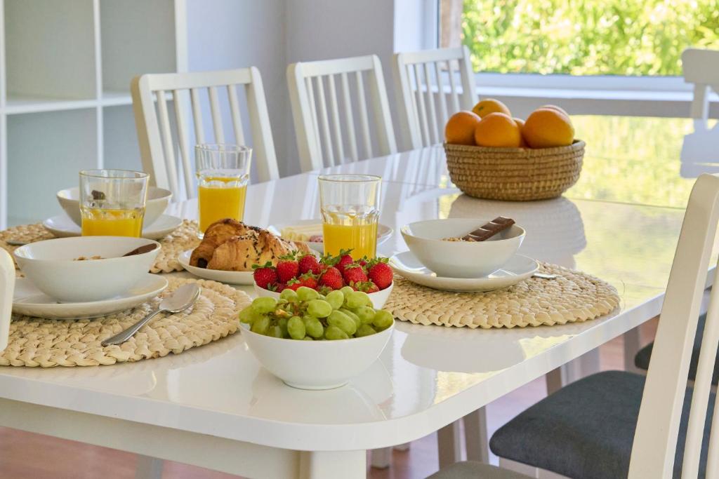 a white table with fruit and juice on it at Beach & Nature Villa with Amazing Pool by TimeCooler in Setúbal