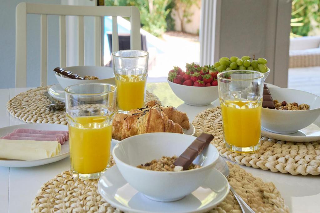 a table with a breakfast of orange juice and food at Beach & Nature Villa with Amazing Pool by TimeCooler in Setúbal