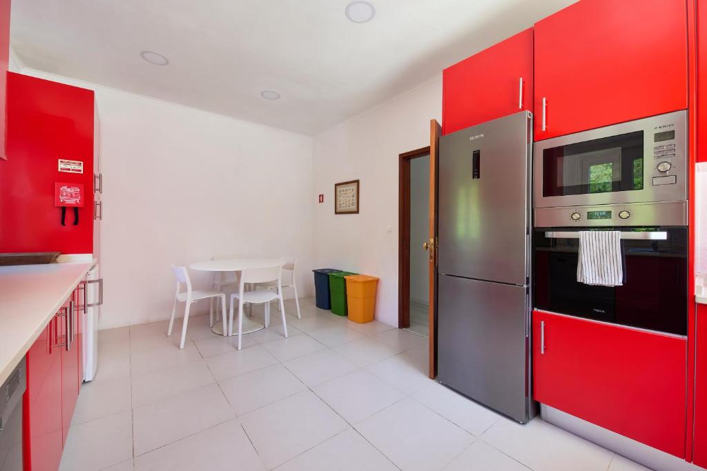 a kitchen with red cabinets and a table and a refrigerator at Beach & Nature Villa with Amazing Pool by TimeCooler in Setúbal