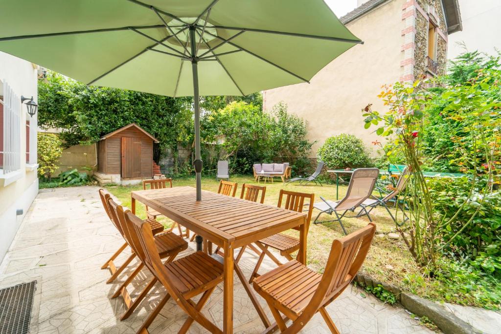 une table en bois avec des chaises et un parasol dans l'établissement Villa Foch, à Aulnay-sous-Bois