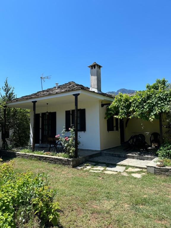 a small white house with a tree in the yard at Elgi Cottage in Chrysi Ammoudia