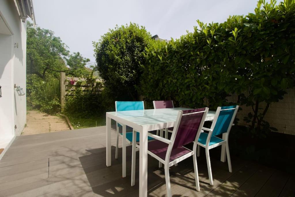 une table blanche et quatre chaises sur la terrasse dans l'établissement Appartement coup de coeur - Terrasse à Biarritz, à Biarritz