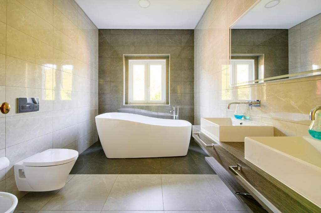 a bathroom with a tub and a toilet and a sink at Beach & Nature Villa with Amazing Pool by TimeCooler in Setúbal