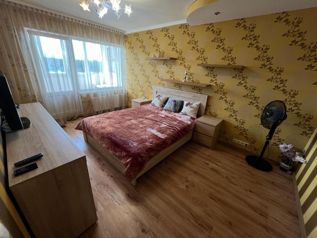 a bedroom with a bed and a yellow wall at saules street apartment in Ventspils