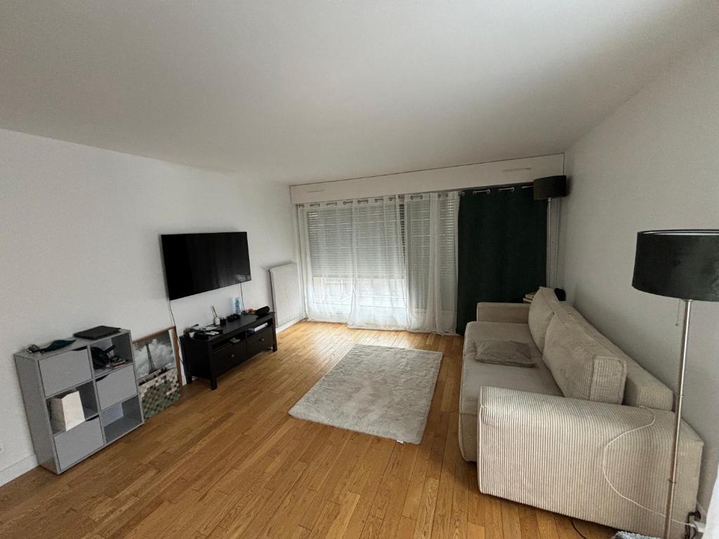 un salon avec un canapé et une télévision à écran plat dans l'établissement T2 Boulogne Billancourt, à Boulogne-Billancourt