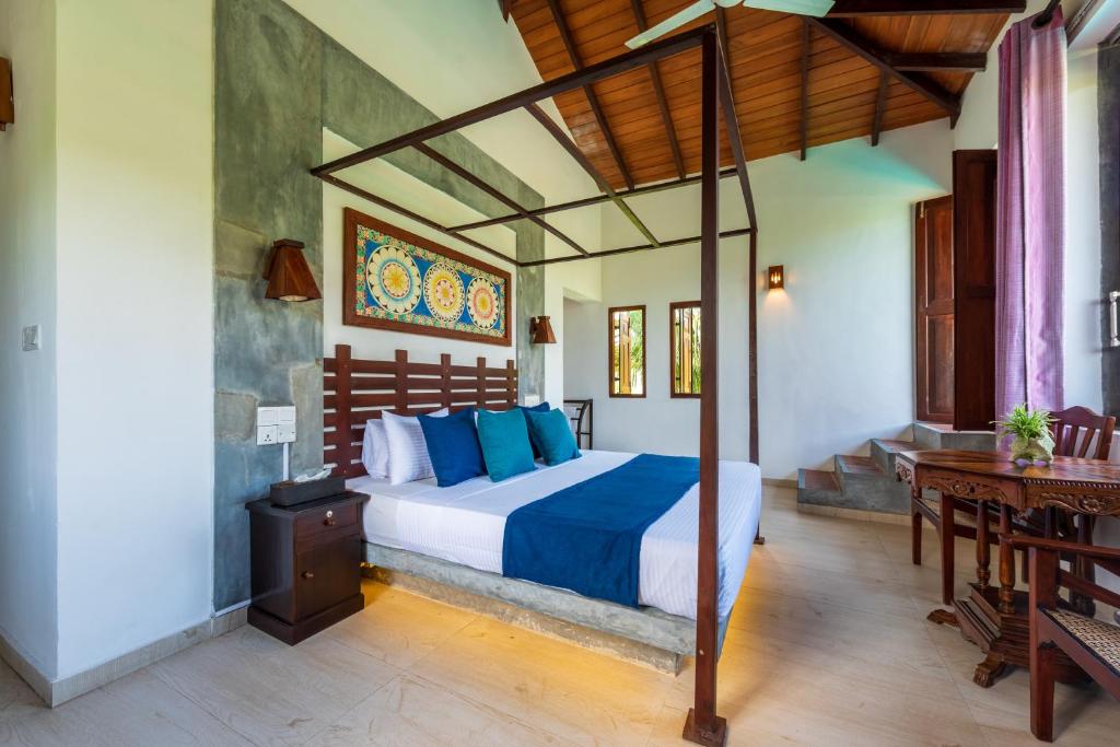 a bedroom with a bed with blue pillows at Anama by Queens Mount in Tangalle