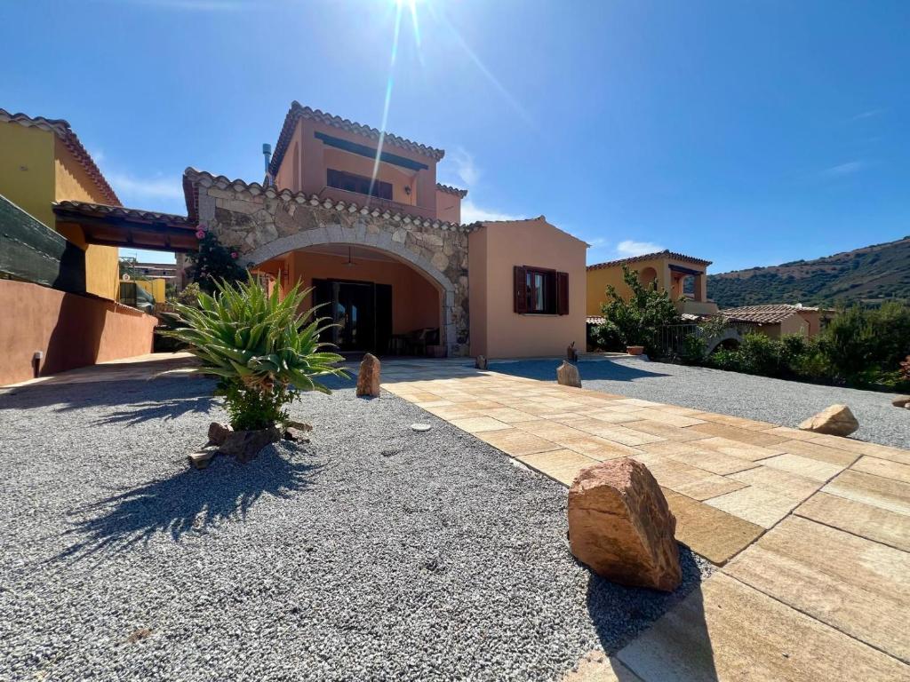 a house with a courtyard with rocks and a building at Villa Sunrise in Budoni