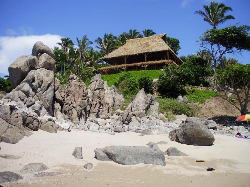 a group of rocks on a beach with a hut at Palapa Ganesh in Sayulita