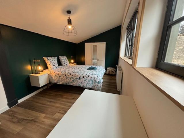 a bedroom with a bed and a green wall at Le Patio de l'Abbaye in Cluny