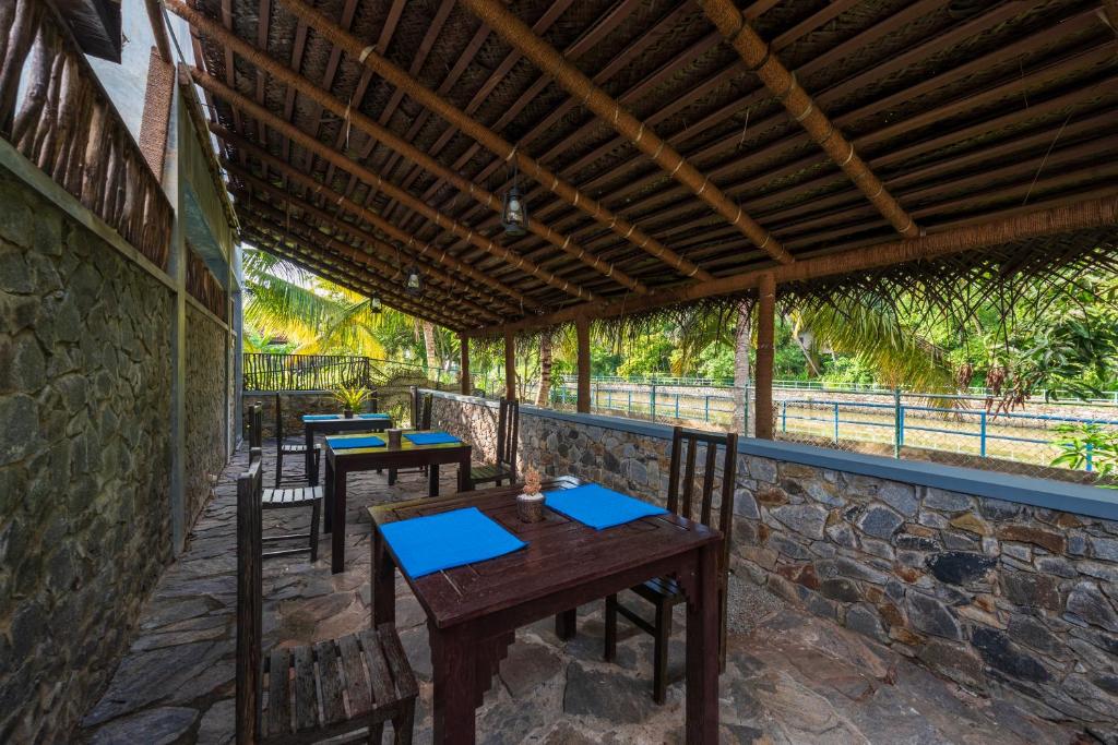a patio with tables and chairs and a stone wall at Anama by Queens Mount in Tangalle