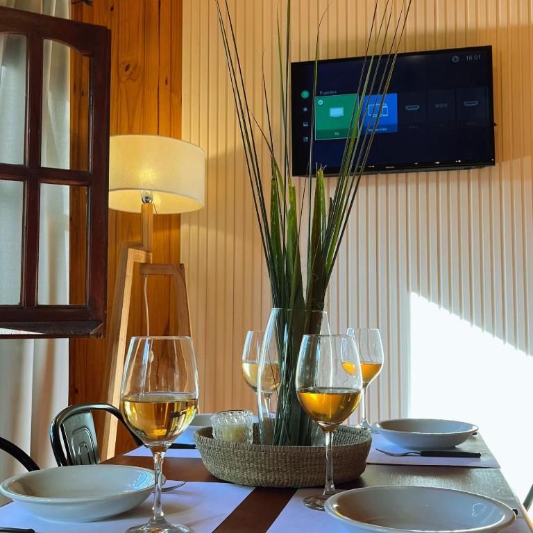a table with wine glasses and a television on a wall at Fratelli Cabañas-Apart in Rosario