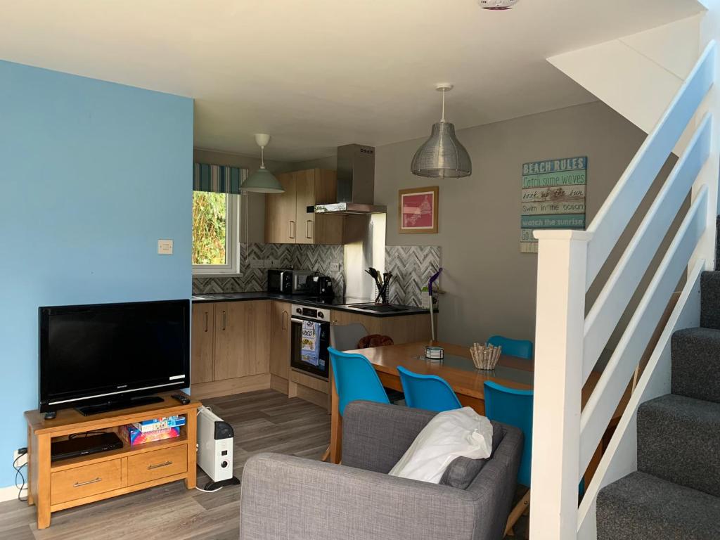 a living room with a television and a table with chairs at Tolroy Manor - 84 Strawberry Hill in Hayle