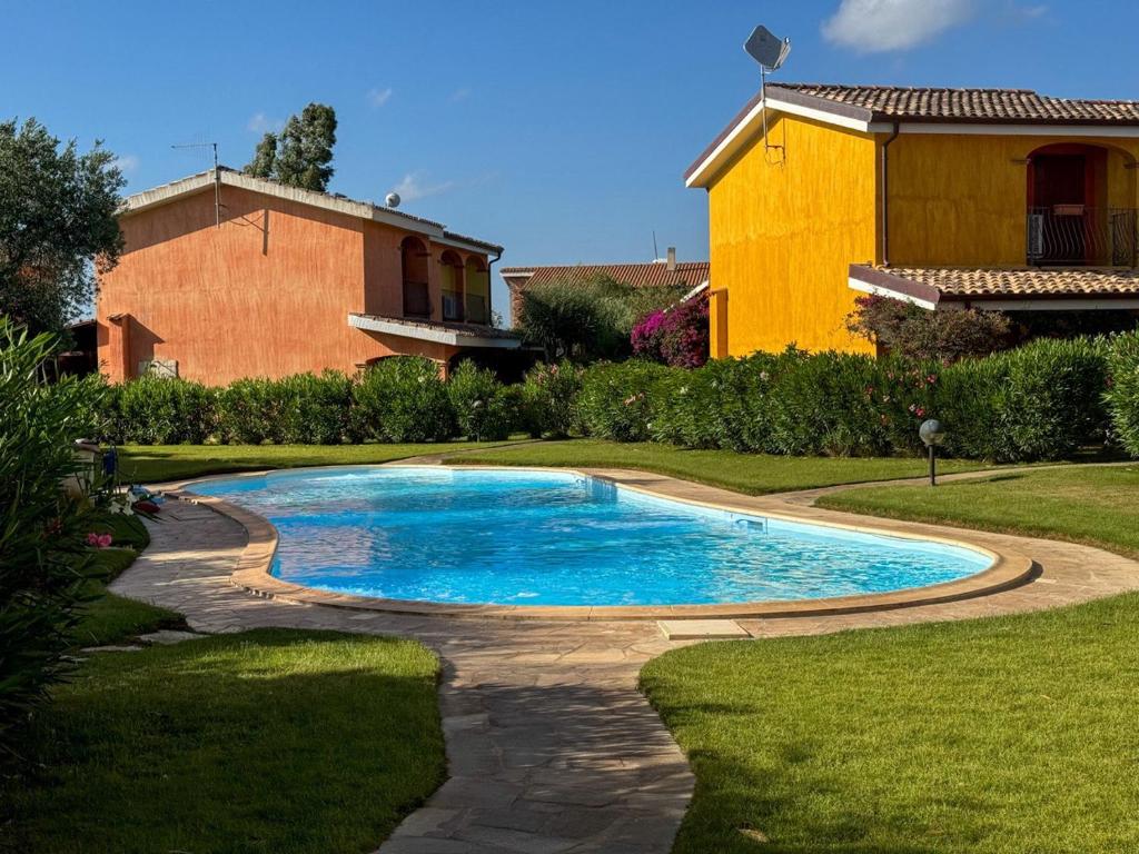 a swimming pool in a yard next to a house at Villa Arianna - Porto Pino in SantʼAnna Arresi