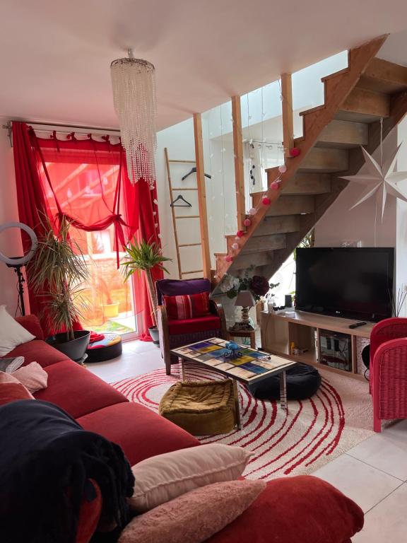- un salon avec un canapé rouge et un escalier dans l'établissement Charmante chambre cosi, à Bretteville-sur-Odon