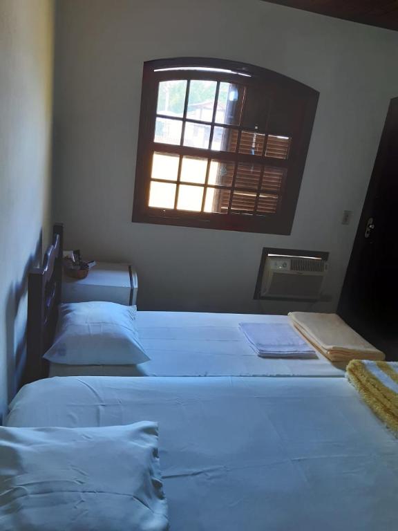 three beds in a room with a window at Gil's suites in Paraty