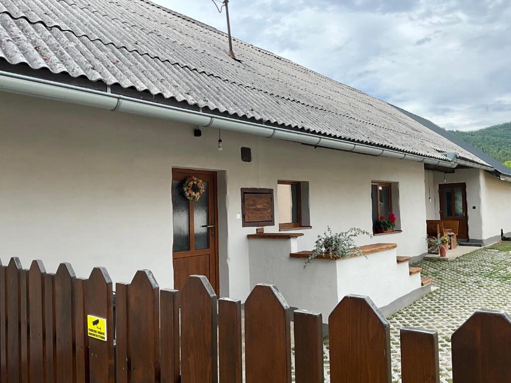a white house with a fence and a wooden door at Vidiecky domček in Pohronská Polhora