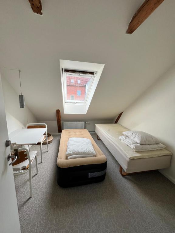 una stanza con due letti, un tavolo e una finestra di Cozy apartment room 1 - free parking in the street a Odense