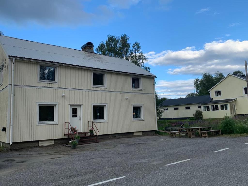 a large white barn with a picnic table and benches at Guldklimpens Vandrarhem in Gunnarn