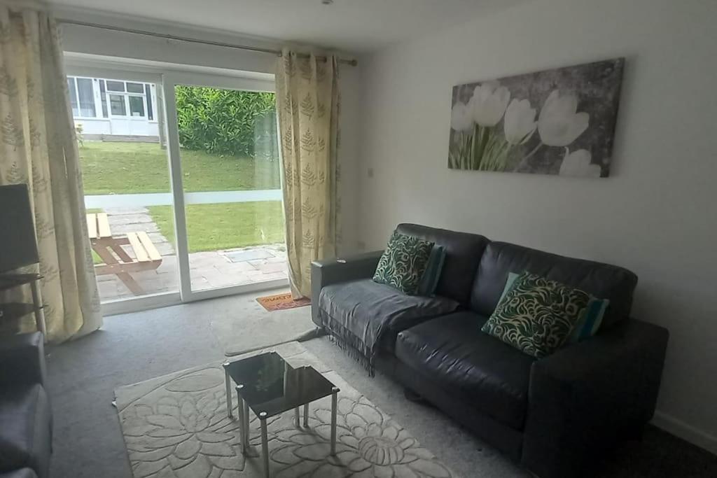 a living room with a black leather couch and a table at Sunny holiday house in Newquay