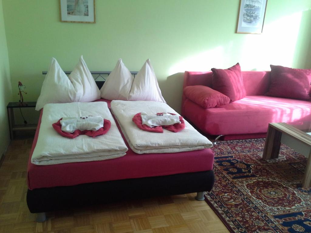 2 Betten in einem Wohnzimmer mit einem rosa Sofa in der Unterkunft Ferienwohnung Burgblick in Kapfenberg