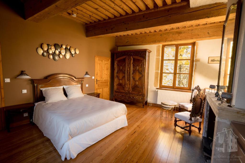 ein Schlafzimmer mit einem Bett und einem Stuhl in einem Zimmer in der Unterkunft Le Relais Des Dames in Neuville-sur-Saône