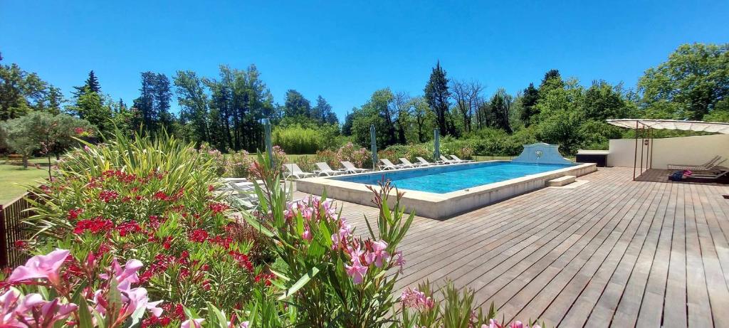 - une piscine dans un jardin avec des chaises et des fleurs dans l'établissement La Bastide des Amouriers, à Caumont-sur-Durance