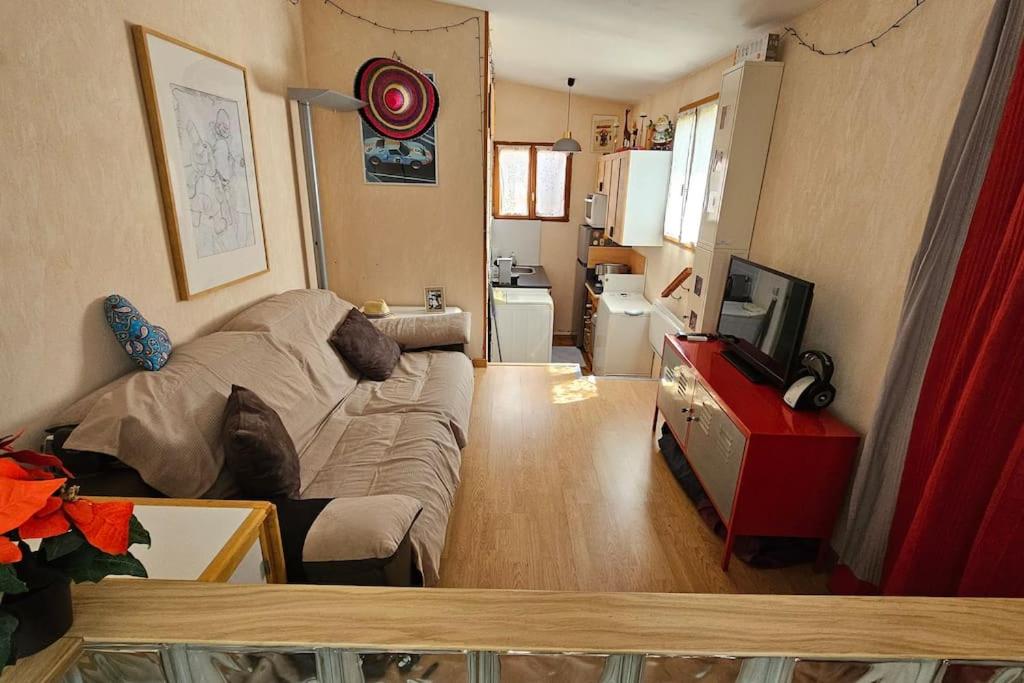 a living room with a couch and a tv at Petite maison avec terrasse in Bezons