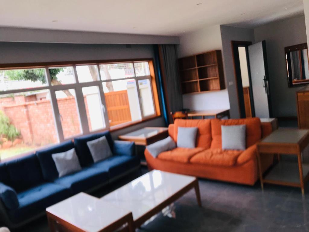 een woonkamer met blauwe en oranje banken en een tafel bij The Reserve in Harare
