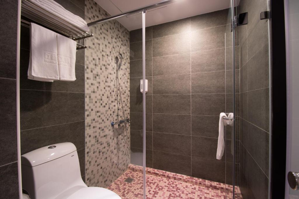 a bathroom with a toilet and a glass shower at Travel Art Inn in Chiayi City
