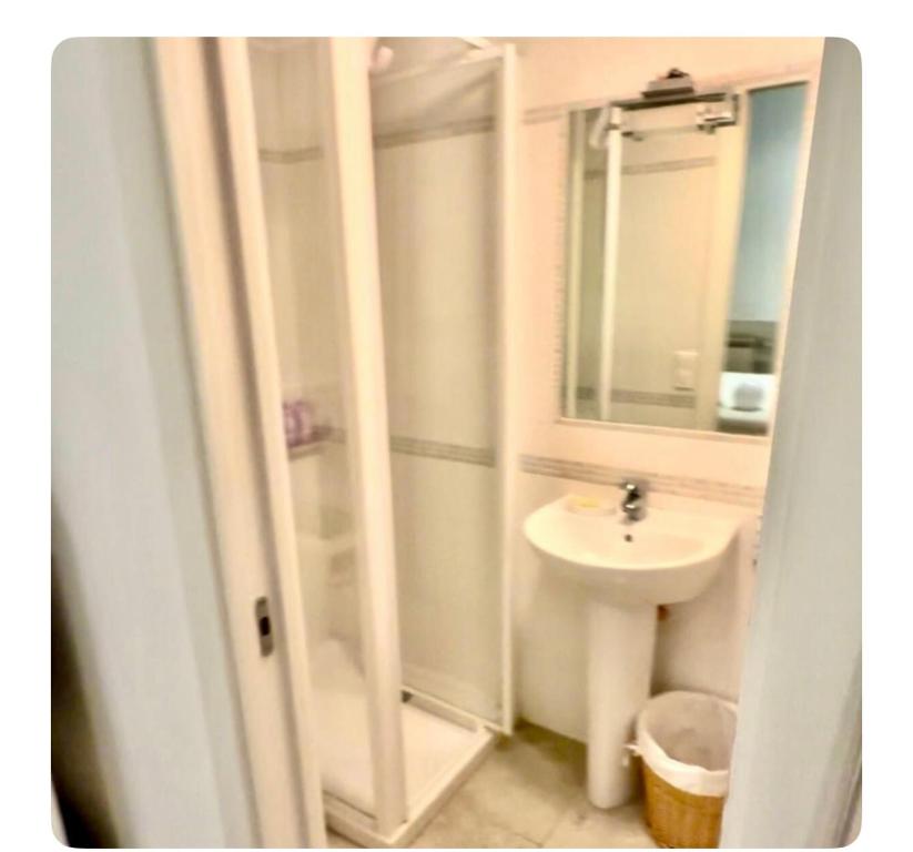 une salle de bain blanche avec un lavabo et un miroir dans l'établissement 2 pièces mezzanine et grande terrasse très calme 30 secondes de monaco, à Beausoleil