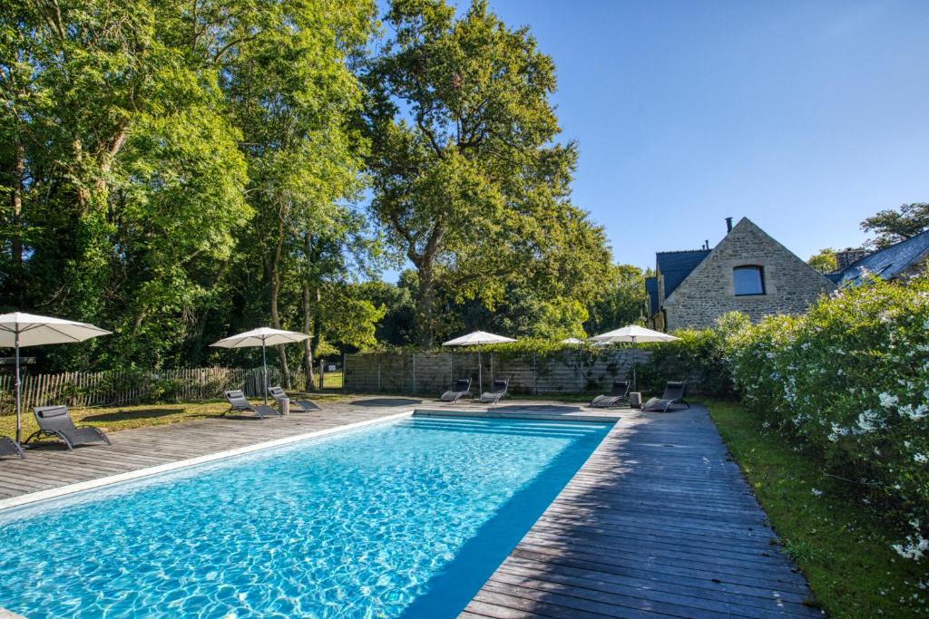 une piscine avec des parasols et une maison dans l'établissement Villa Piscine & Presqu'île, à Carnac